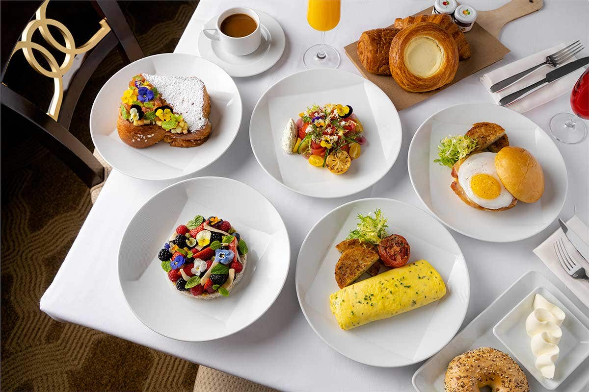 An assortment of breakfast dishes, including pastries, an omelette, toast with berries, and a plate with eggs and salad.