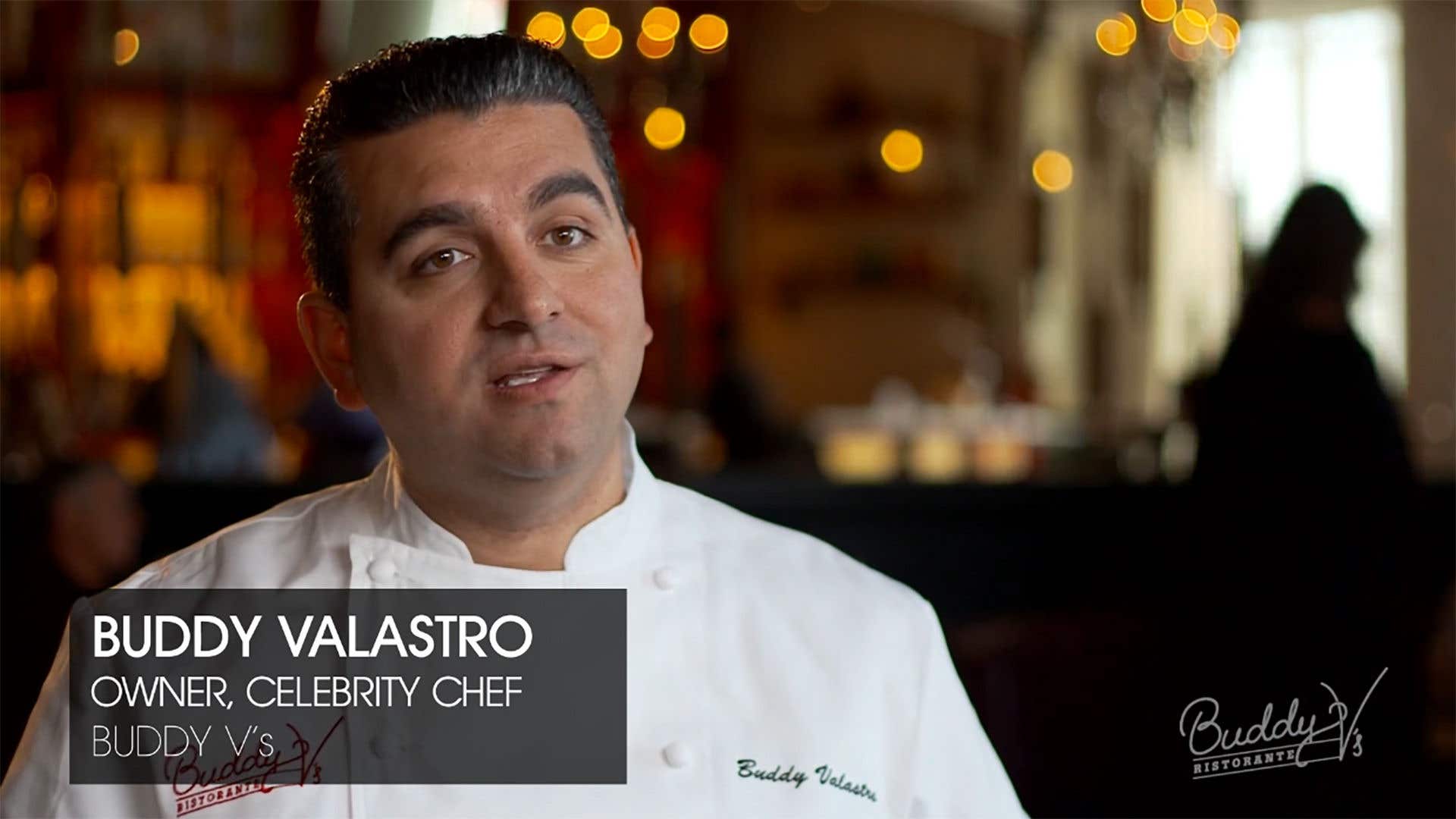 Executive Chef Buddy Valastro in a white chef’s coat during a restaurant interview, with Buddy V’s Ristorante branding on screen.