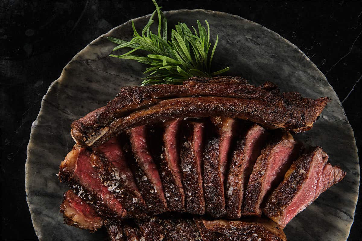 Cooked slices of meat laid out on a plate with the bones laid above it. 
